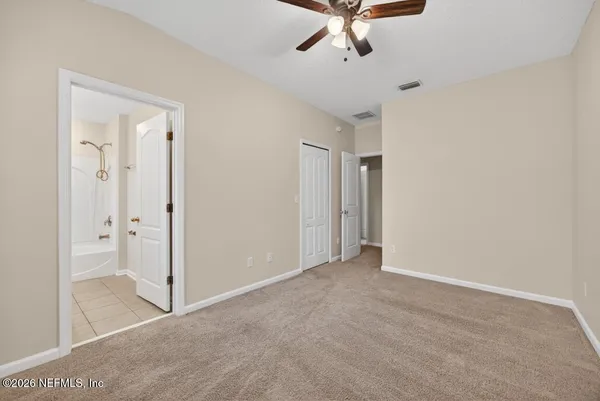 an empty room with a ceiling fan and carpet