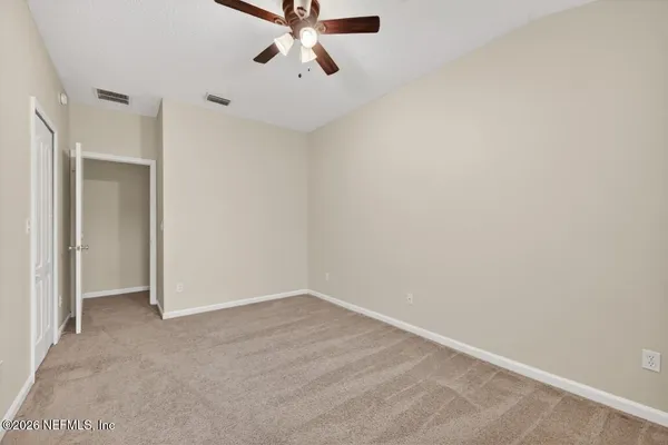 an empty room with chandelier fan and windows