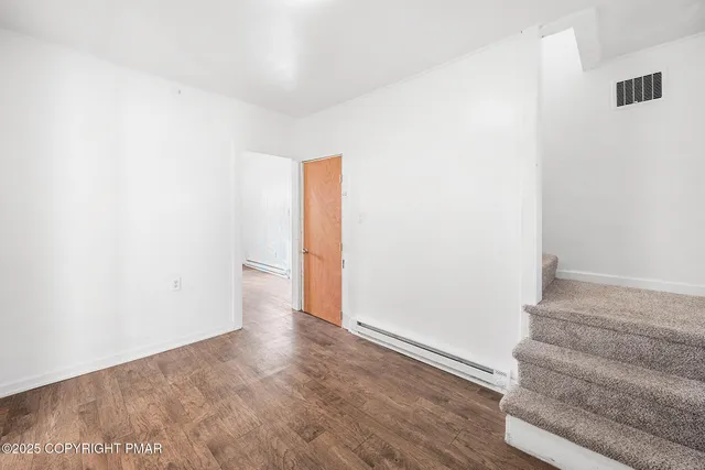 a view of an empty room with wooden floor