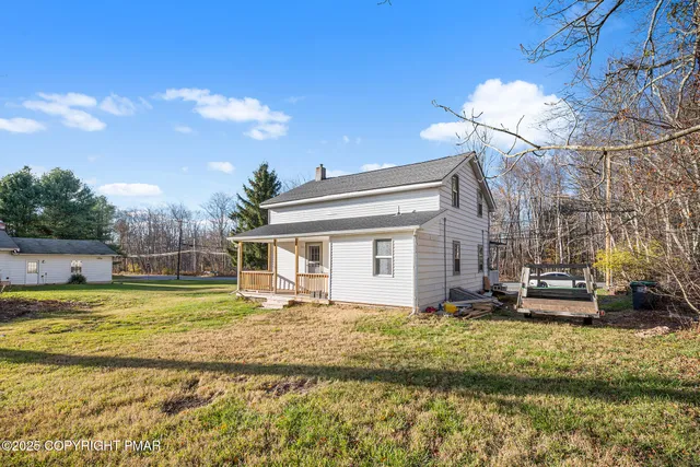 a view of a house with a big yard and large trees