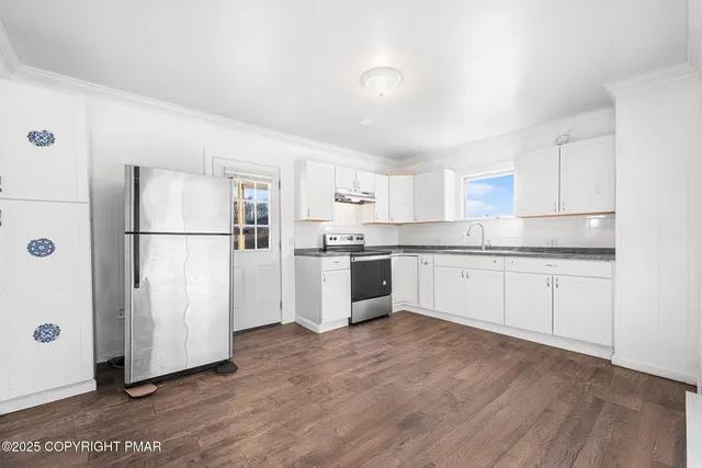 a kitchen with stainless steel appliances granite countertop a refrigerator sink and white cabinets