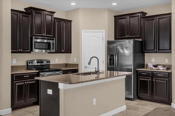 a kitchen with granite countertop a stove top oven and refrigerator