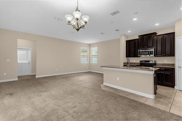 a view of kitchen with stainless steel appliances granite countertop refrigerator stove microwave and cabinets