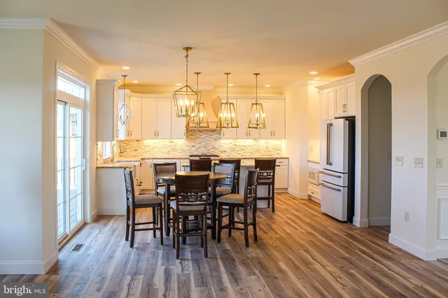 a kitchen with stainless steel appliances a dining table chairs stove refrigerator and cabinets