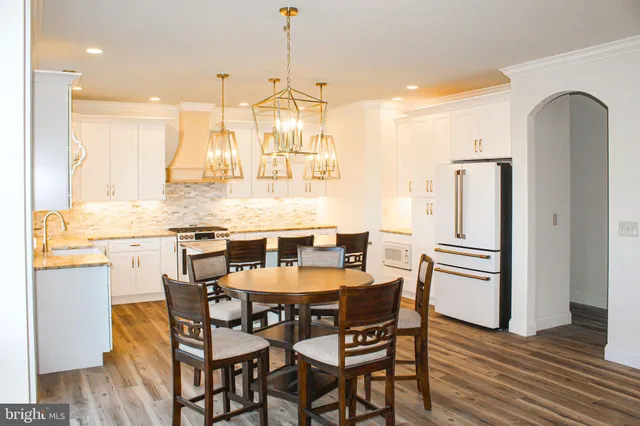 a kitchen with stainless steel appliances granite countertop a dining table chairs and granite counter tops