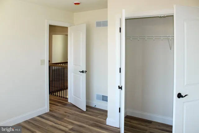 a view of a hallway with wooden floor and closet area