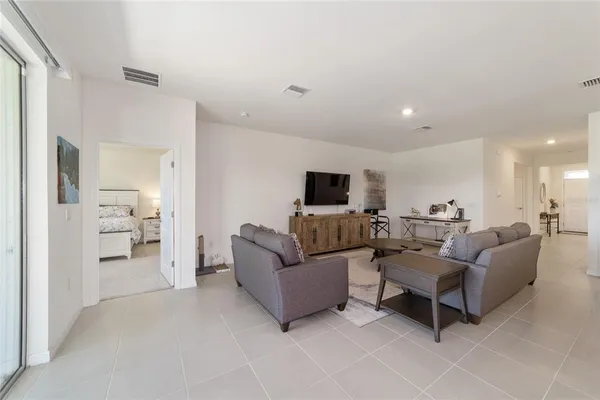 a living room with couches and kitchen view with kitchen island
