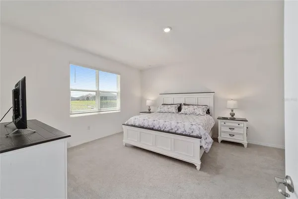 a bedroom with a bed and a flat screen tv in white dresser