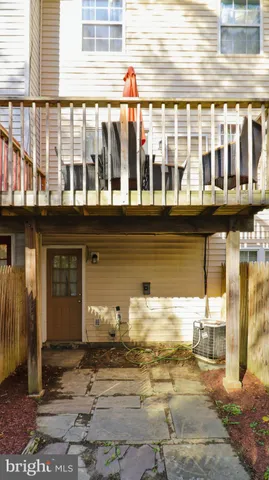 a view of a pathway of a building with a bench and potted plants