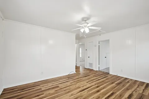 a view of a bedroom with wooden floor and ceiling fan