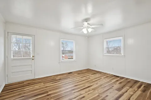 a view of empty room with wooden floor and fan