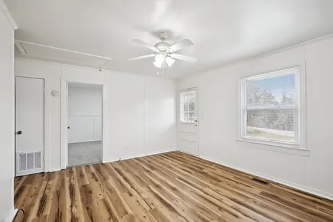 a view of empty room with wooden floor and fan