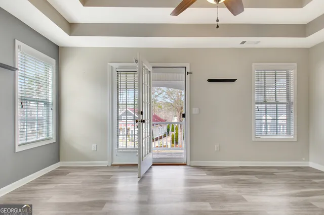 a view of an empty room with window and hardwood floor