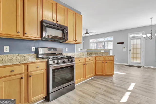 a kitchen with stainless steel appliances granite countertop a stove a sink and a microwave