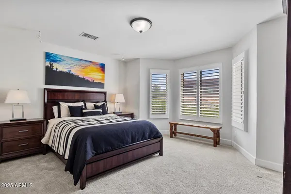 a spacious bedroom with a bed and painting on the wall