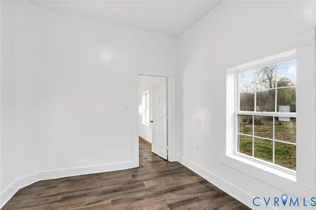 a view of an empty room with wooden floor and windows