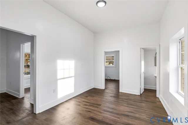 an empty room with wooden floor & windows and bathroom