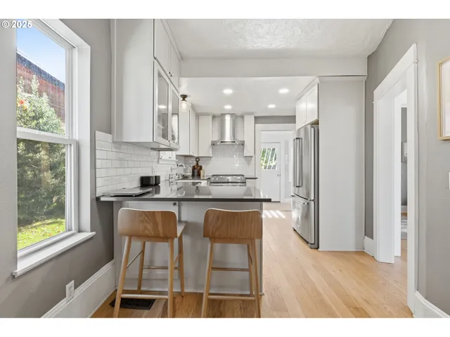 a kitchen with stainless steel appliances kitchen island granite countertop a table chairs sink and cabinets
