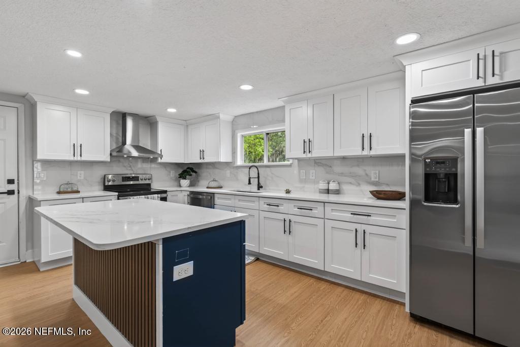 43739 Ratliff Road Callahan, FL 32011 - Photo 29 of 55 a kitchen with stainless steel appliances granite countertop a refrigerator a sink dishwasher a stove and white cabinets with wooden floor