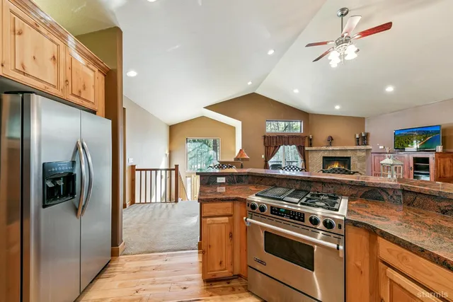 a kitchen with stainless steel appliances granite countertop a stove a refrigerator and a sink with wooden floor