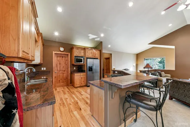 a kitchen with stainless steel appliances kitchen island granite countertop a table chairs in it and wooden floors