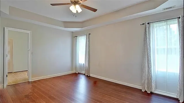 an empty room with wooden floor and ceiling fan