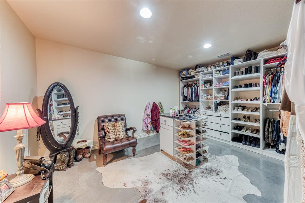2337 Walsh Road Olney, TX 76374 - Photo 37 of 38 Spacious walk-in closet featuring extensive built-in shelving, multiple hanging rods, integrated drawers, and a central storage island with a dark countertop