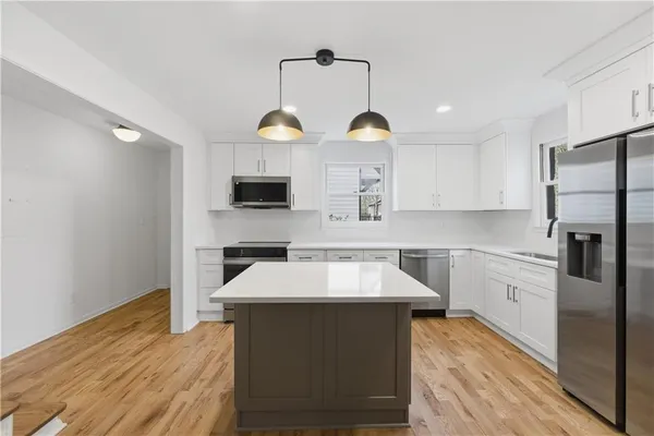 a kitchen that has a lot of white cabinets and stainless steel appliances