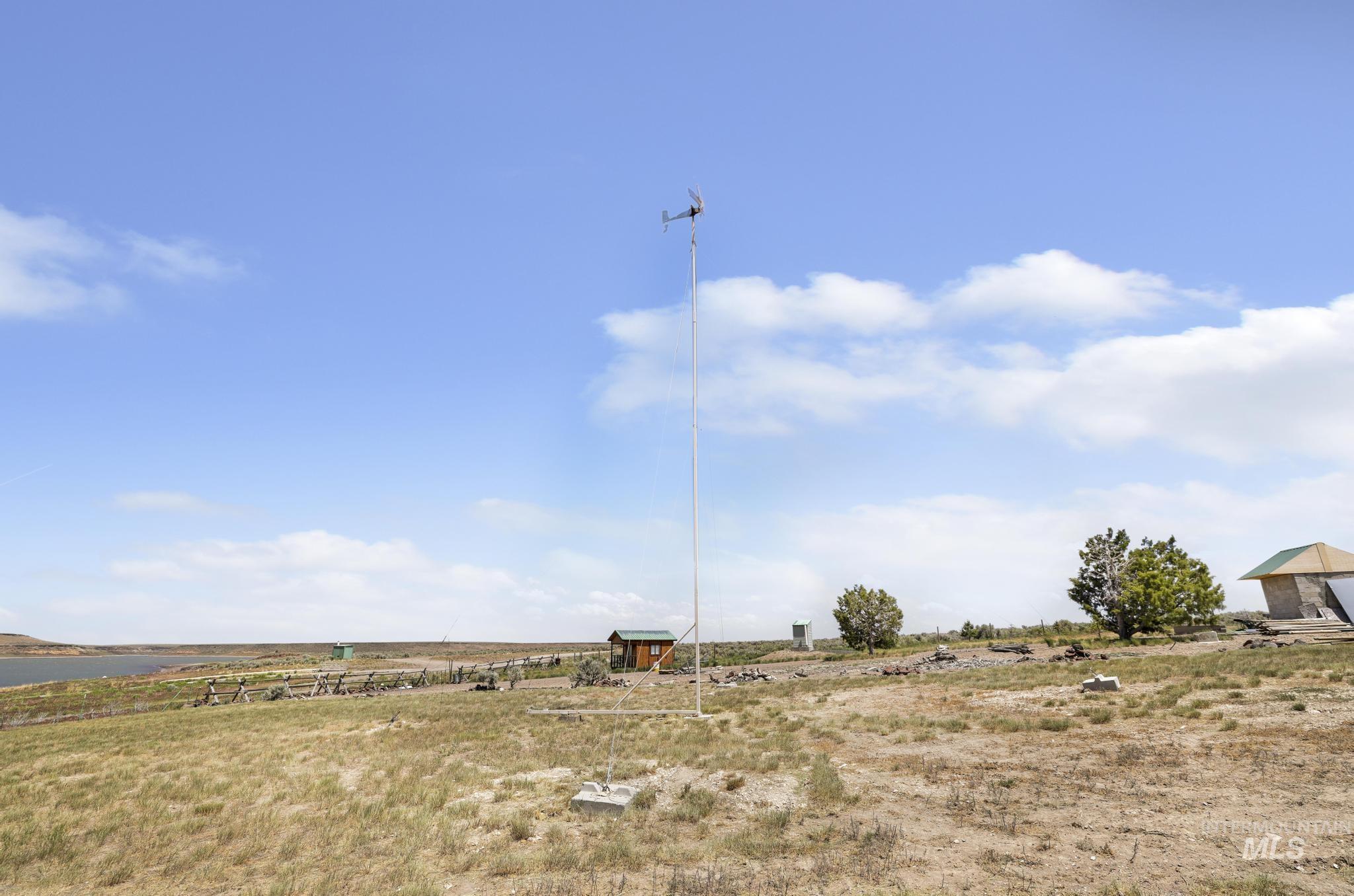 758 Cedar Crk Road Rogerson, ID 83302 - Photo 26 of 50 Expansive open terrain with natural vegetation, featuring a tall weather station, a rustic wooden outbuilding, and distant water