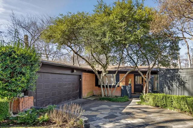 a front view of a house with a tree