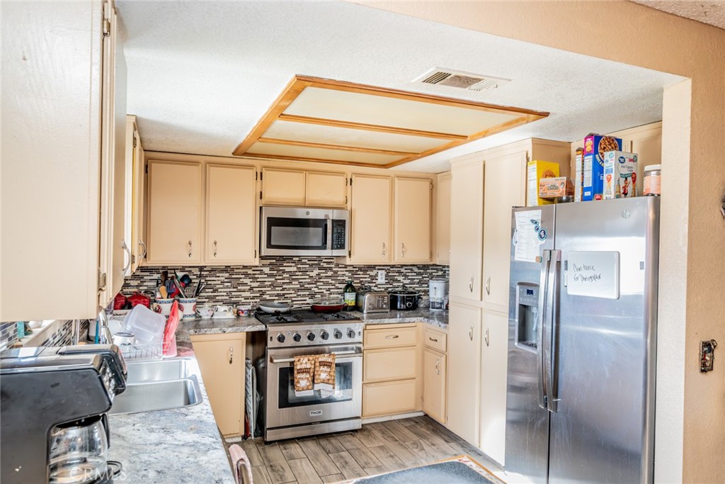 4637 Luna Road Phelan, CA 92371 - Photo 17 of 43 a kitchen with stainless steel appliances kitchen island granite countertop a refrigerator and a stove top oven