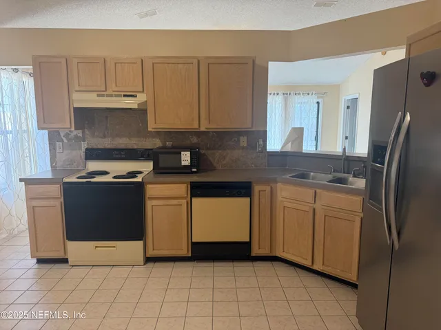 a kitchen with stainless steel appliances granite countertop a stove a sink and a refrigerator