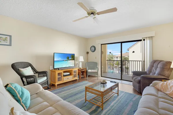 a living room with furniture a flat screen tv and a floor to ceiling window