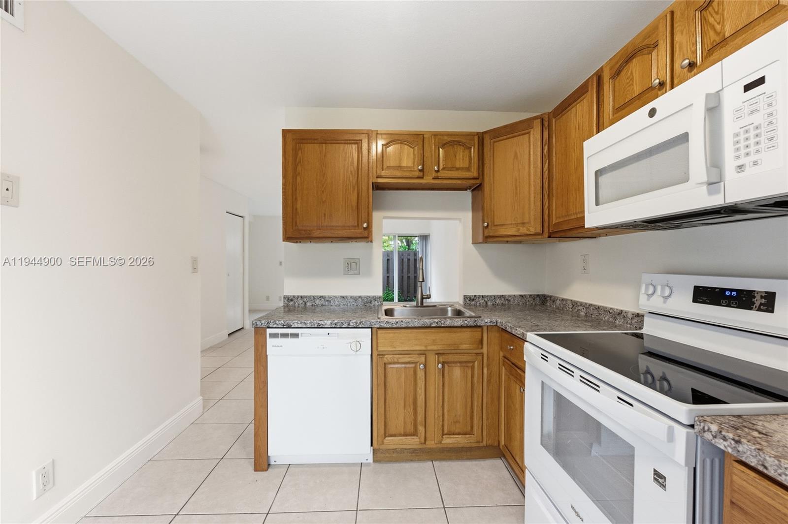 3003 Northwest 5th Terrace, Unit 2 Pompano Beach, FL 33064 - Photo 6 of 28 a kitchen with a stove top oven sink and cabinets