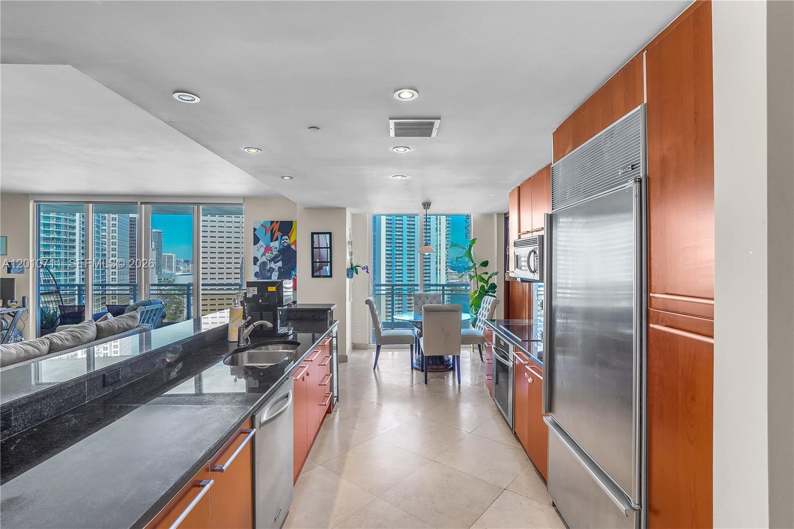 901 Brickell Key Boulevard, Unit 2807 Miami, FL 33131 - Photo 11 of 29 a kitchen with stainless steel appliances granite countertop a refrigerator a sink dishwasher a stove and a dining table with wooden floor