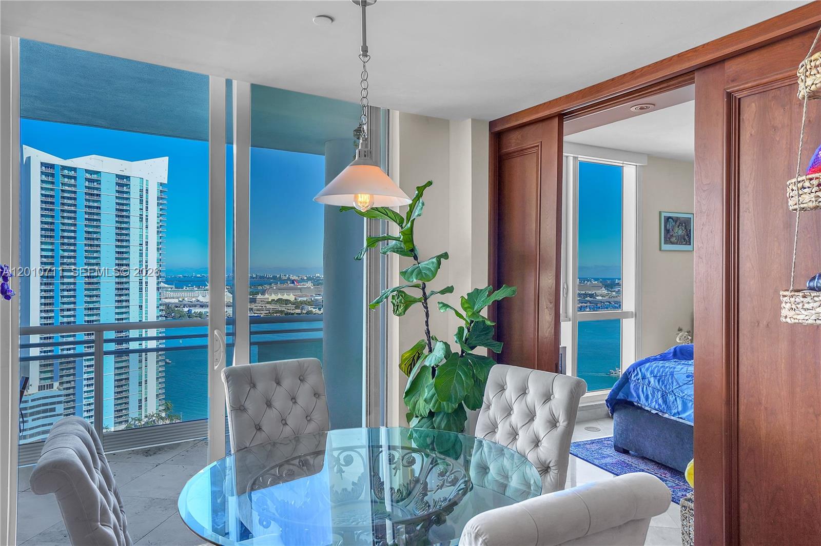 901 Brickell Key Boulevard, Unit 2807 Miami, FL 33131 - Photo 12 of 29 a living room with furniture potted plant and a glass door