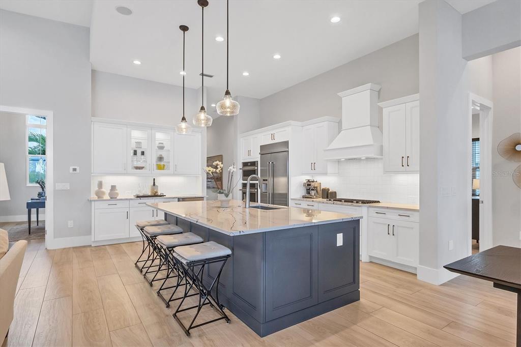 8477 Pavia Way Lakewood Ranch, FL 34202 - Photo 8 of 67 a large kitchen with stainless steel appliances kitchen island granite countertop a large center island a sink a stove and a refrigerator