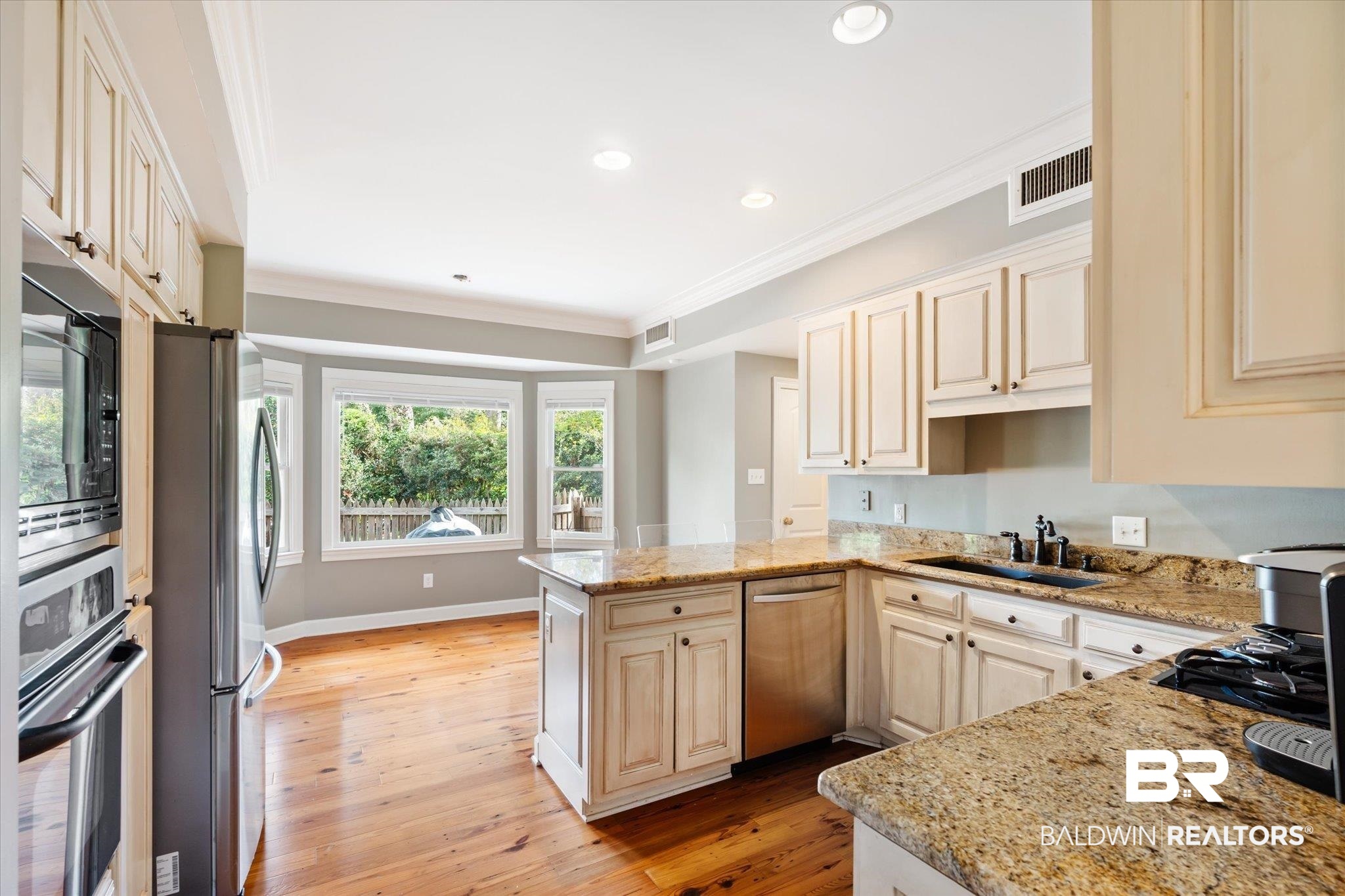 11 Drury Lane Mobile, AL 36608 - Photo 11 of 34 Kitchen with light stone countertops, light hardwood / wood-style flooring, appliances with stainless steel finishes, and kitchen peninsula