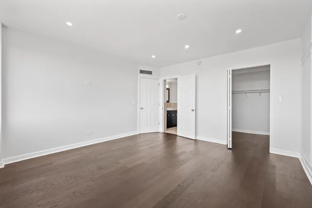 a view of an empty room with wooden floor and closet