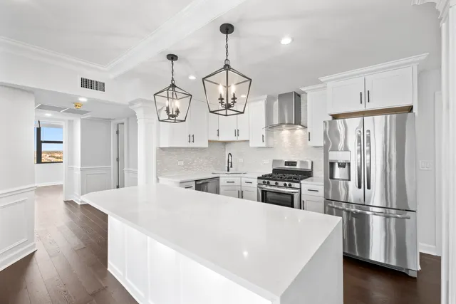 a kitchen with stainless steel appliances granite countertop a refrigerator a stove a sink dishwasher and a dining table with wooden floor