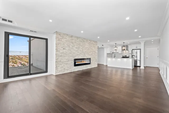 an empty room with wooden floor and a kitchen