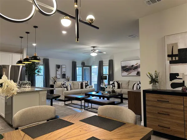 a living room with furniture a rug kitchen view and a chandelier