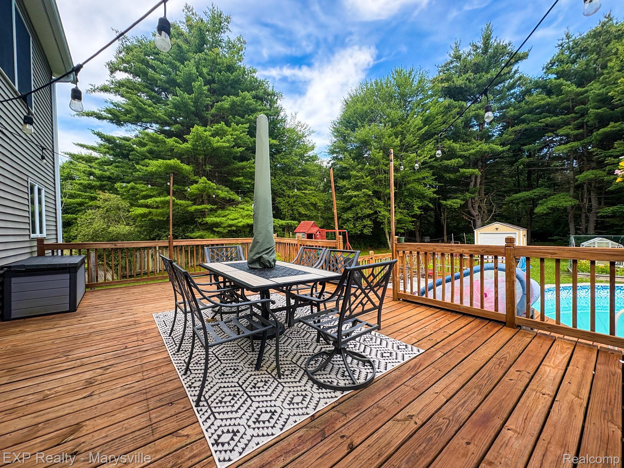 5538 Klettner Road St. Clair, MI 48079 - Photo 10 of 46 Spacious wood-finish deck featuring string lighting, a perimeter railing, and an above-ground pool