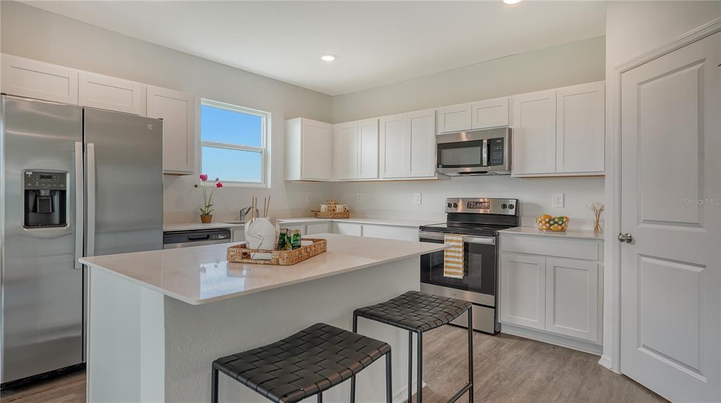 13113 Bayberry Way Parrish, FL 34219 - Photo 7 of 20 a kitchen with stainless steel appliances a sink a stove a refrigerator cabinets and a dining table
