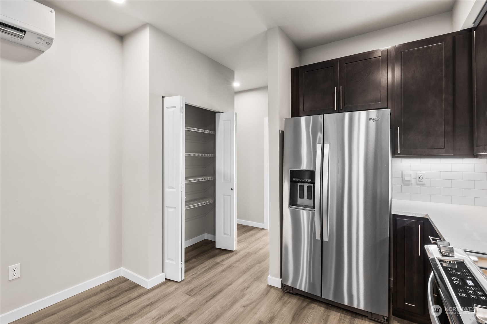 23413 Edmonds Way, Unit E1 Edmonds, WA 98026 - Photo 10 of 27 a view of a refrigerator in kitchen and an empty room with wooden floor
