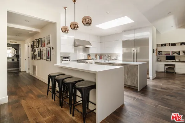 a kitchen with stainless steel appliances kitchen island granite countertop a table chairs sink and cabinets