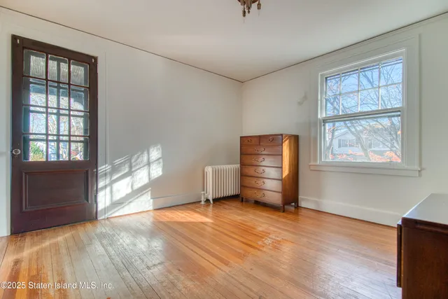 an empty room with wooden floor cabinet and windows