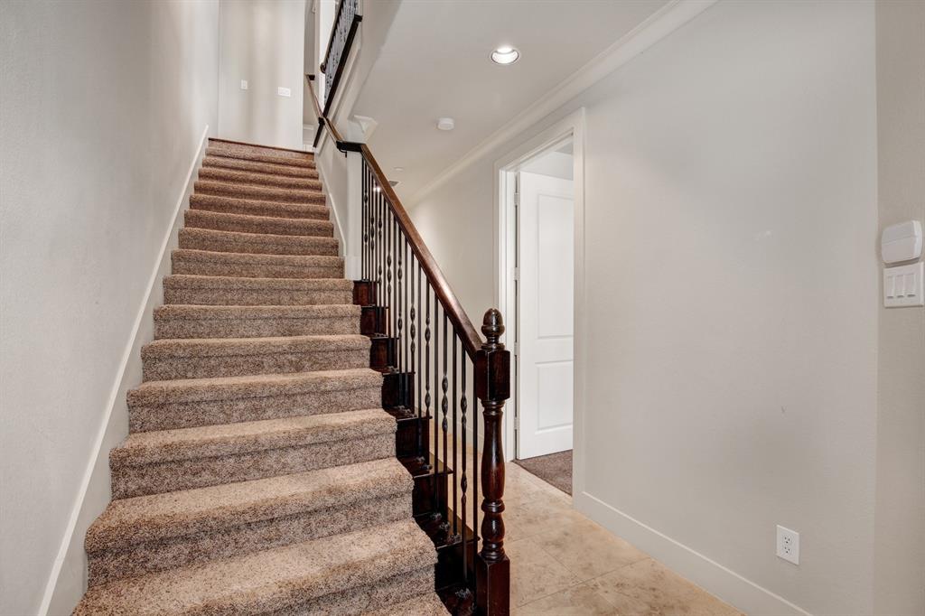 4111 Rawlins Street, Unit 403 Dallas, TX 75219 - Photo 2 of 23 Carpeted staircase with dark wood newel post and wrought iron balusters