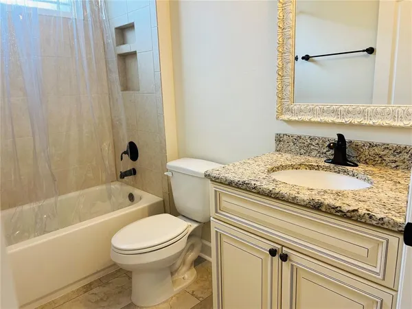 a bathroom with a granite countertop toilet sink a mirror a bathtub and shower