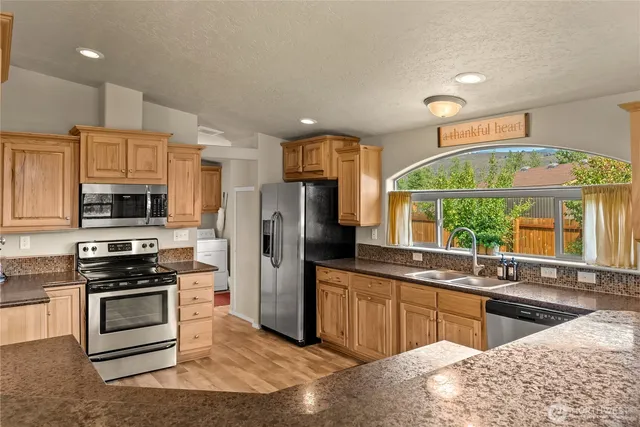 a kitchen with stainless steel appliances kitchen island granite countertop a stove and a sink